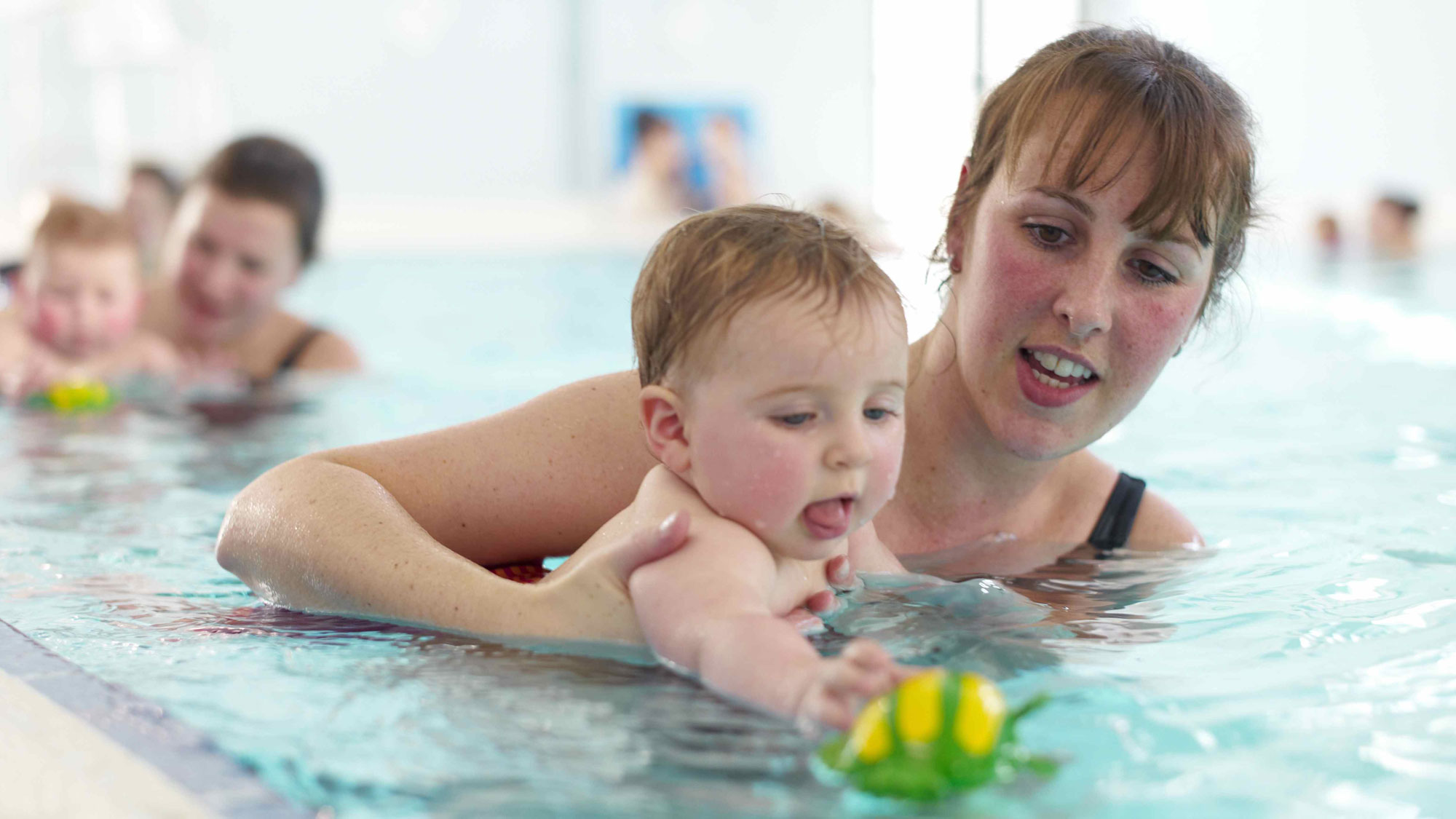 Mother and baby in pool playing with toy