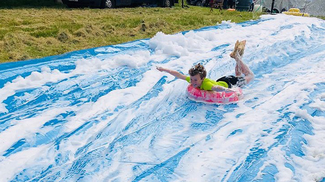 Child on the foam slip 'n' slide at the Scouts Fundays event.